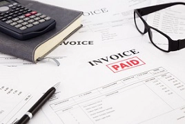 calculator, glasses over paid invoice