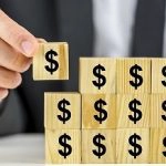 businessman assembling blocks with dollar signs